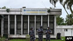 FILE - Police officers wearing face masks stands outside the Pasteur Institute of Ivory Coast, near Abidjan, May 11, 2020.