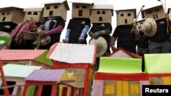 FILE - People wear house models during a march on World Habitat Day in Phnom Penh, Oct. 5, 2015. Former residents of Boeung Kak Lake, Borei Keila neighbourhood and other communities affected by private corporation developers called on the Cambodian government to stop evicting them from their homes.