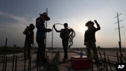 Workers are silhouetted at the construction site of a bridge in Krasang Chrum village on the outskirts of Phnom Penh, Cambodia, Thursday, May 14, 2020. (AP Photo/Heng Sinith)