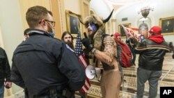 FILE - In this Jan. 6, 2021, Jake Angeli, a QAnon conspiracy supporter, is confronted by U.S. Capitol Police officers outside the Senate Chamber inside the Capitol in Washington. (AP Photo/Manuel Balce Ceneta, File)