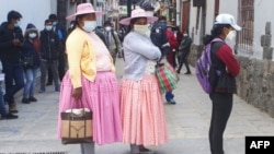 Mujeres peruanas usan barbijo mientras hacen fila frente a un banco en Puno, Perú, el 5 de octubre de 2020.