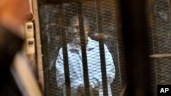 Misrda inqilobdan keyin prezidentlikka saylangan va ikki yil o'tib ag'darilgan Muhammad Mursiy pnajara ortida 