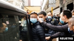 Stand News acting chief editor Patrick Lam, one of the six people arrested "for conspiracy to publish seditious publication" according to Hong Kong's Police National Security Department, is escorted by police as they leave after the police searched his of