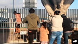 (File) In this Jan. 8, 2020, photo, people seeking asylum in the United States wait at the border crossing bridge in Tijuana, Mexico, just across the border from San Diego.