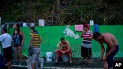 ជន​​រង​គ្រោះ​ដោយ​ព្យុះ​សង្ឃរា Maria រង់​ចាំ​​ទឹក​ដែល​បូម​ចេញ​ពី​កូន​ព្រែក​នៅលើ​ភ្នំ នៅ​តំបន់ Naranjito កោះ Puerto Rico កាល​ពី​ថ្ងៃទី​២៨ ខែ​កញ្ញា។ ពលរដ្ឋ​តំបន់​នេះ​ពឹង​អាស្រ័យ​លើ​ទឹក​នេះ​សម្រាប់​ប្រើ​ប្រាស់​ក្រោយ​ពេល​ប្រព័ន្ធ​ទឹក​ត្រូវ​បាន​ខូច​ខាត​ដោយ​ខ្យល់​ព្យុះ។