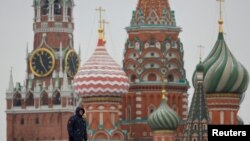 A security specialist stands guard near the Spasskaya tower of the Kremlin and St. Basil’s Cathedral in central Moscow, Feb. 13, 2025.