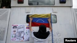 Un partidario del líder de oposición venezolano Juan Guaidó, a quien muchas naciones reconocen como el presidente interino del país, coloca una bandera nacional durante una manifestación contra el gobierno del presidente en disputa Nicolás Maduro. Julio 5, 2019.