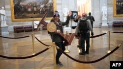 WASHINGTON, DC - JANUARY 06: A pro-Trump protester carries the lectern of U.S. Speaker of the House Nancy Pelosi through the Roturnda of the U.S. Capitol Building after a pro-Trump mob stormed the building on January 06, 2021 in Washington, DC…
