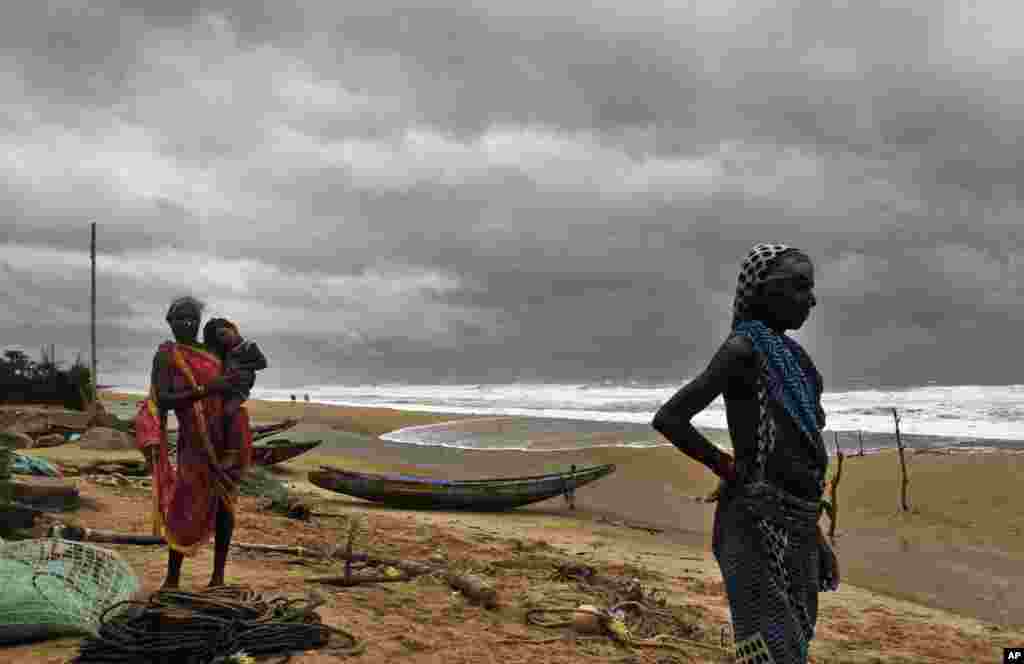 Women watch the sea waves before evacuating the place near Podampeta village, on the outskirts of Gopalpur beach in Ganjam district, Oct. 11, 2014.