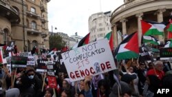 Watu wakusanyika wakiwa na mabango na bendera za Palestina kushiriki maandamnao ya kuwaunga mkono Wapalestina huko London Oktoba 14, 2023.
