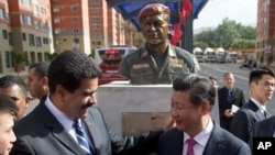 El presidente en disputa de Venezuela, Nicolás Maduro, bromea con su homólogo chino, Xi Jinping, durante una visita a un edificio de apartamentos construido con fondos chinos en Caracas. Imagen de archivo del 21 de julio de 2014.