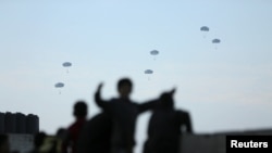 Las personas observan mientras el ejército estadounidense realiza su primer envío de ayuda sobre Gaza, en medio del conflicto continuo entre Israel y Hamás, en la ciudad de Gaza.