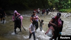 Migrantes caminan con niños en su viaje hacia la frontera con Estados Unidos, en Acandi, Colombia, el 9 de julio de 2023.