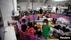 Menores migrantes no acompañados, de 3 a 9 años, ven TV en la instalación de Aduanas y Protección Fronteriza de EE. UU., en Donna, Texas, el 30 de marzo de 2021.