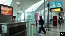 A woman enters the face and iris-recognition gate to board a plane, during a media tour at Dubai Airport, in the United Arab Emirates, Sunday, March 7, 2021. (AP Photo/Kamran Jebreili)