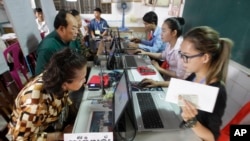 Voters, left, sit for registering their names during a voter registration process of the National Election Committee (NEC) in Phnom Penh, Cambodia, Thursday, Sept. 1, 2016. NEC started its three-month-long voter registration in the day for the next general election scheduled for July 2018. (AP Photo/Heng Sinith)