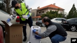 Members of Lebanese NGO Baytna Baytak Firas Minnawi, right, and Mario Suleiman, left, unpack oxygen machine to be donated to an elderly COVID-19 patient in Beit Shebab, a mountain village 15 mile (24 km) north of Beirut, Lebanon, Wednesday, Jan. 27, 2021. (AP Photo/Bilal Hussein)