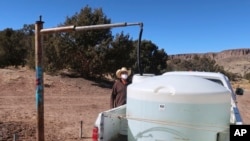 Phillip Yazzie waits for a water drum in the back of his pickup truck to be filled in Teesto, Ariz., on the Navajo Nation, on Feb. 11, 2021. AP/Felicia Fonseca.