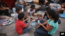 Children migrants play cards at an encampment set up by migrants near a Mexican immigration office in Matamoros, Mexico, Wednesday, July 31, 2019, on the border with the U.S. (AP Photo/Emilio Espejel)