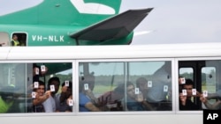  FILE - A group of asylum seekers hold up their identity cards after landing in Manus Island, Papua New Guinea. The United States has agreed to resettle an unspecified number of refugees languishing in Pacific island camps.