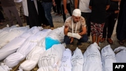 Ông Mahmoud Al-Areer ngồi bên xác con mình cùng những người khác sau vụ oanh kích của Israel ở miền nam Dải Gaza hôm 21/10.