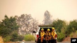 Firefighters ride in the back of a pickup truck while battling the LNU Lightning Complex fires, Aug. 23, 2020, in unincorporated Lake County, Cailf. 