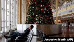 FILE - Andres Alarcon, 29, of Colombia and a student at Washington's Howard University, sleeps by a Christmas tree inside of Reagan National Airport in Washington, on Saturday, Dec. 19, 2009.