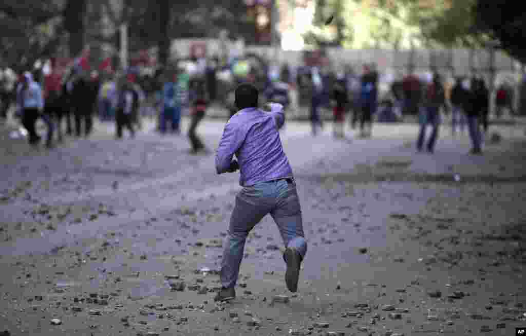 Pro and anti-government protesters throw stones during clashes near Tahrir Square in Cairo, Egypt, January 30, 2013. 