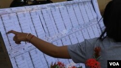 ប្រជាពលរដ្ឋនៅក្នុងឃុំអរិយក្សត្រផ្ទៀងផ្ទាត់ឈ្មោះនៅក្នុងការិយាល័យមួយ មុនចូលទៅបោះឆ្នោត។ (ស៊ុន ណារិន/VOA)