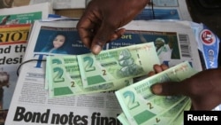 ARCHIVES - Un vendeur de rue montre les nouveaux billets dans la capitale de Harare, Zimbabwe, le 28 novembre 2016.