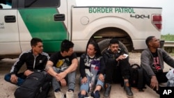 Migrantes colombianos que intentaban evadir a la Patrulla Fronteriza de EEUU esperan ser procesados cerca del puerto de entrada en Hidalgo, Texas, el 4 de mayo de 2023.