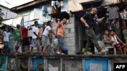 មន្រ្តី​នៃអាជ្ញាធរ​ប្រឆាំង​ការជួញដូរ​គ្រឿងញៀន​ហ្វីលីពីន​(រូបស្តាំ) នាំជន​សង្ស័យ​អំឡុងពេល​ឆ្មក់បង្ក្រាប​ប្រជាជន​រស់នៅ​អាណាធិបតេយ្យ​នៅទី​បញ្ចុះសព​សាធារណៈ​ក្នុងរដ្ឋធានី​ម៉ានីល ថ្ងៃ១៦​ ខែមីនា​ ឆ្នាំ​២០១៧។