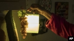 ARCHIVO - Las compañías productoras de energía hidroelétrica anunciaron este martes en Ecuador que inician racionamientos ante la sequía que castiga al país. Esta imagen ilustrativa mustra una lampara de mano sostenida por una mujer durante apagón en Puerto Rico en julio de 2018.