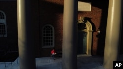 Matt Chan, un estudiante de la Universidad de Harvard, come pizza afuera del edificio del campus, mientras la escuela permanece cerrada y las clases pasaron a ser virtuales debido al coronavirus. Jueves 26 de marzo de 2020 en Cambridge, Massachusetts