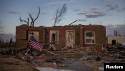 A US flag is tied to a fallen tree in front of a destroyed residence in the aftermath of a tornado in Mayfield, Ky.,Dec. 14, 2021.