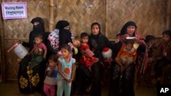 Rohingya Muslim refugee women with their children wait at a nutrition center to collect the diet for their children at Balukhali refugee camp 50 kilometres (32 miles) from, Cox's Bazar, Bangladesh, Jan. 23, 2018. 