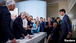 Waziri Mkuu wa Canada Justin Trudeau na viongozi wa G7 Waziri Mkuu wa Uingereza Theresa May, Rais wa Ufaransa Emmanuel Macron, Chansela wa Ujerumani Angela Merkel, Waziri Mkuu wa Japan Shinzo Abe na Rais wa Marekani Donald Trump wakijadiliana juu ya makubaliano ya pamoja, Jumamosi, Juni 9, 2018.