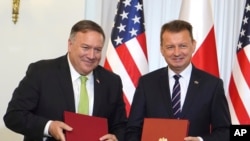 U.S. Secretary of State Mike Pompeo, left, and Poland's Minister of Defence Mariusz Blaszczak pose for the media after signing the US-Poland Enhanced Defence Cooperation Agreement in the Presidential Palace in Warsaw, Poland Aug. 15, 2020.