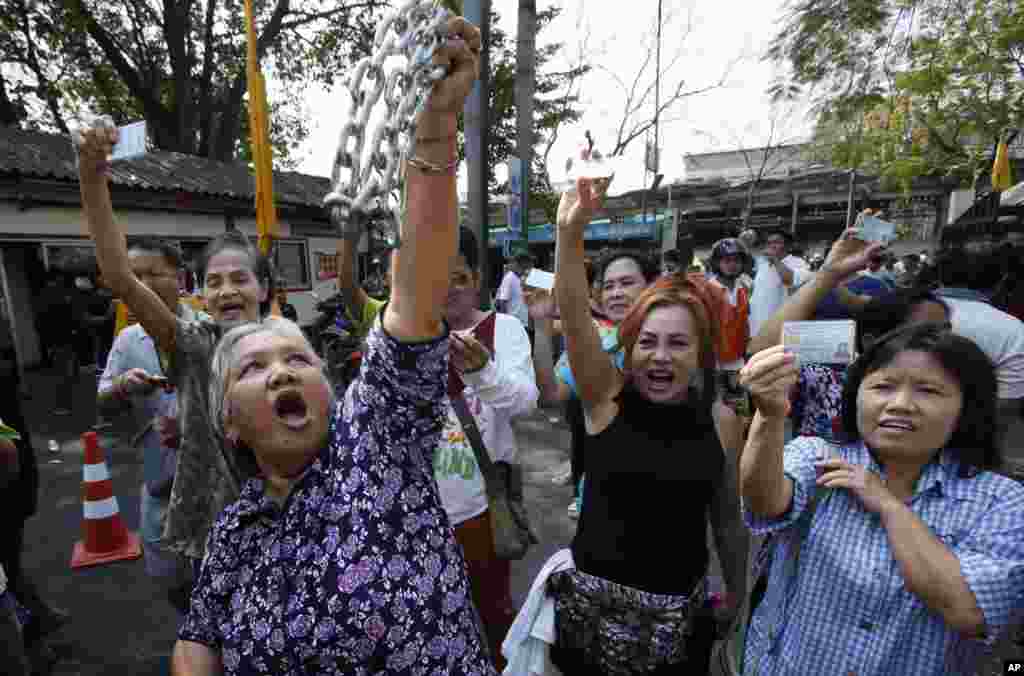 Voters hold their identification cards and the chains that held the gate of the polling station closed, as they demand the right to vote during general elections in Bangkok, Feb. 2, 2014.