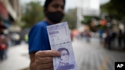 Una mujer muestra un nuevo billete de 500.000 bolívares, al moneda de curso legal, después de retirarlo de un banco en Caracas, el 16 de marzo de 2021.