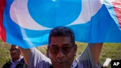 អ្នក​គាំទ្រ​គណបក្ស​យុត្តិធម៌​ពលរដ្ឋ​ (People's Justice Party) ម្នាក់​បក់​ទង់​របស់​គណបក្ស​នេះ​នៅ​ខាង​ក្រៅ​វិមាន​ជាតិ​នៅ​ក្នុង​ក្រុង​គូឡាឡាំពួ ប្រទេស​ម៉ាឡេស៊ី កាលពី​ថ្ងៃទី២៦ ខែកុម្ភៈ ឆ្នាំ២០២០។