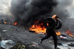 A demonstrator holds tires as he runs during a protest against Ecuador's President Lenin Moreno's austerity measures in Quito, Ecuador October 12, 2019. REUTERS/Ivan Alvarado