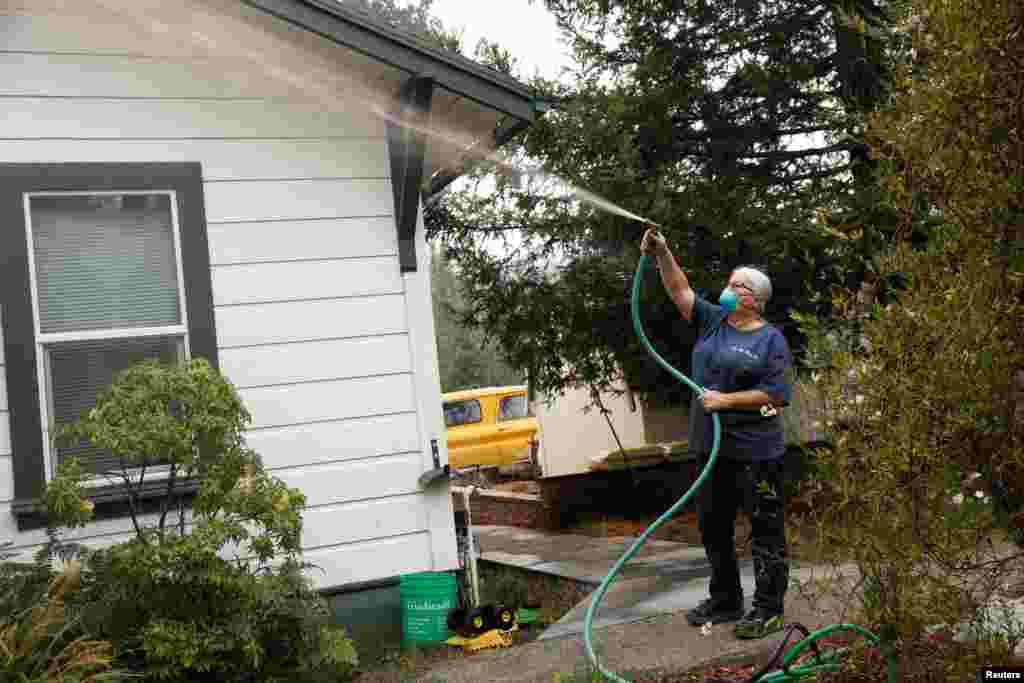 Vicki Nightingale sprays water on her home in Glen Ellen, California, Oct. 11, 2017.