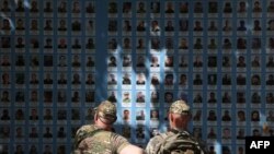 Двоє українських військових перед "Стіною пам’яті полеглим за Україну" у центрі Києва, 20 травня 2024 року. На думку історика Тімоті Снайдера, Україна своїм спротивом "продовжує 1938 рік", дозволяючи уникнути війни між великими державами. (Фото Анатолія СТЕПАНОВА / AFP)