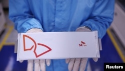 Zaposlenik pozira za fotografije sa baterijom za EV u fabrici baterija SK On EV u Seosanu