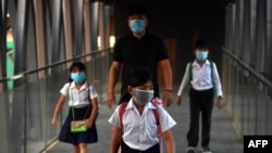 FILE - Students wearing face masks to prevent the spread of Covid-19 coronavirus walk on an overpass on their way to school in Phnom Penh on February 1, 2021.
