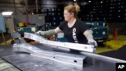 FILE - United Auto Workers line worker Crystal McIntyre unloads parts from a stamping machine at the General Motors Pontiac Metal Center in Pontiac, Mich., April 30, 2015.