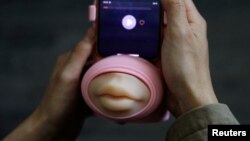 Jing Zhiyuan uses a remote kissing device "Long Lost Touch", as he demonstrates how to use it during an interview with Reuters, at his home in Beijing