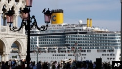 In this file photo, a cruise ship passes by St. Mark's Square filled with tourists, in Venice, Italy, Sunday, June 2, 2019. (AP Photo/Luca Bruno)