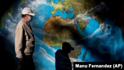 A man wearing a mask walks past graffiti depicting a globe in the Orcasitas neighborhood in Madrid, Spain, Monday, Sept. 28, 2020. 